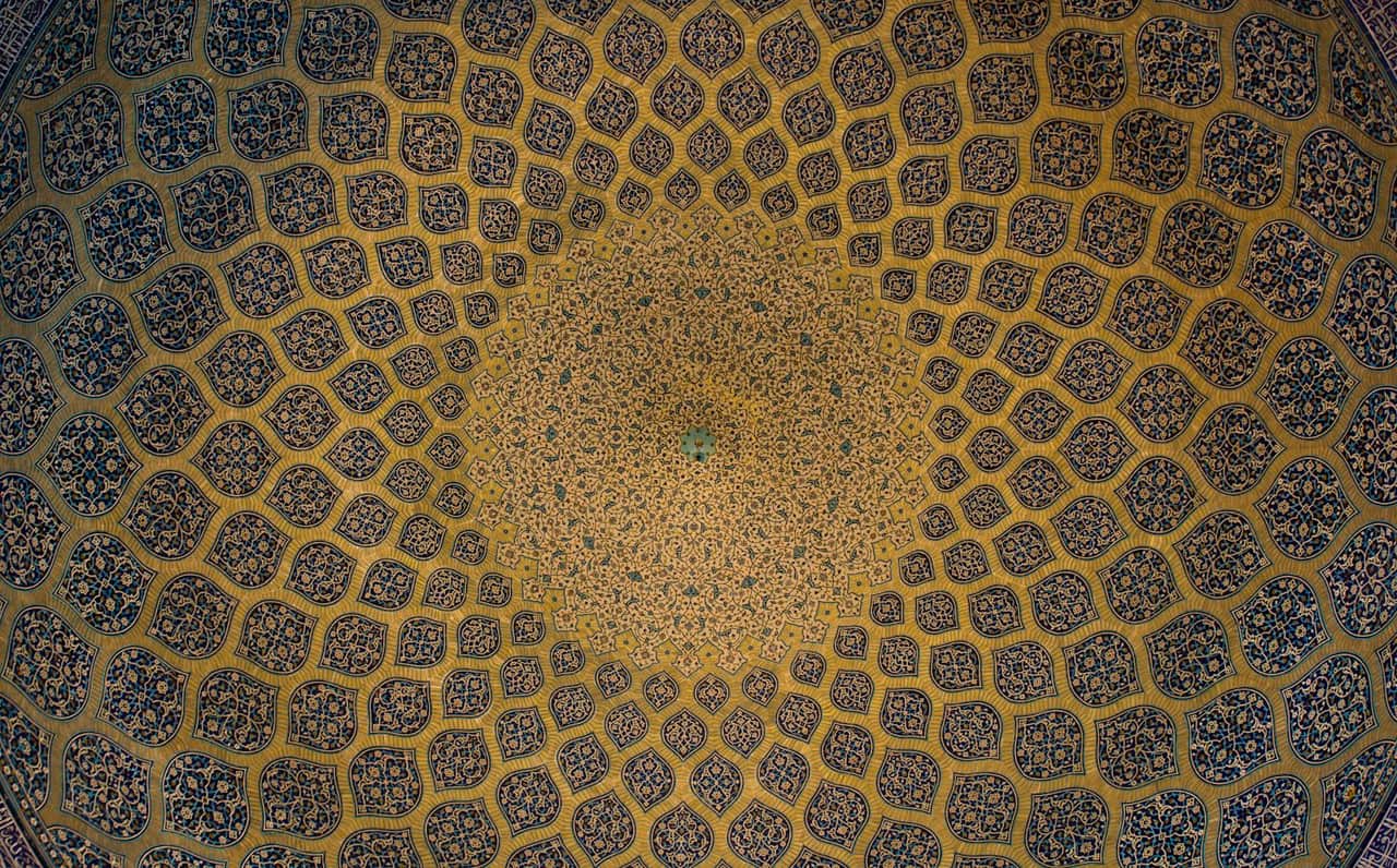Kubbe tavanda merkezden yayılan mavi-altın geometrik çini desenleri